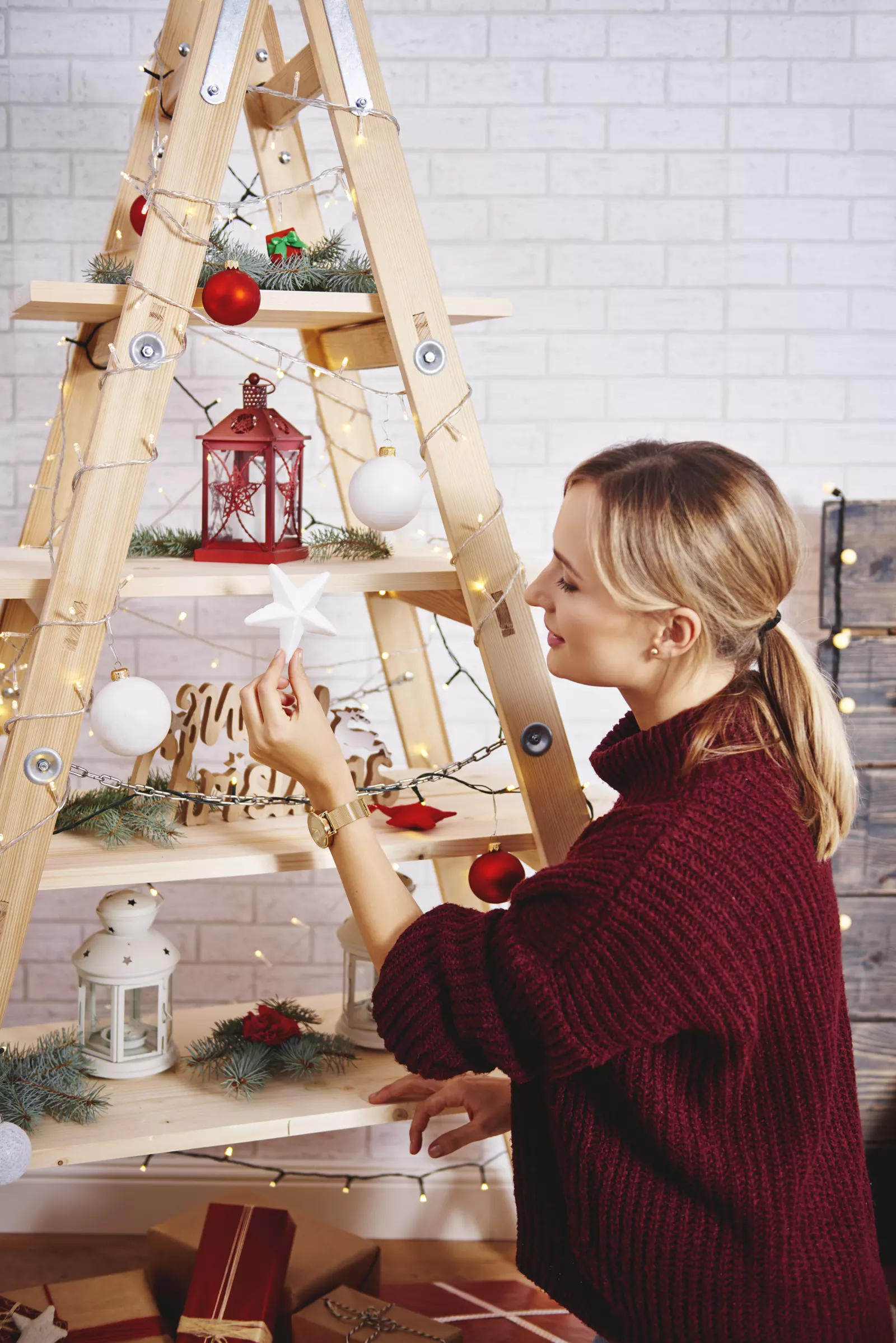 Young woman hanging ornaments while decorating a Christmas tree at home
